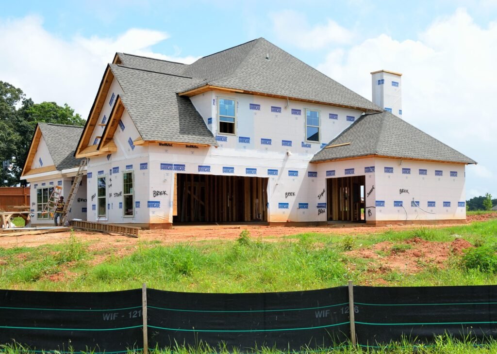 Newly constructed custom home with exterior wrapping, construction materials visible, and a ladder; represents the home building process in South Florida.
