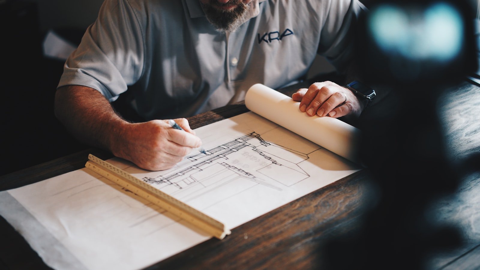 Man drafting architectural plans on paper, emphasizing construction management for luxury home projects in South Florida.