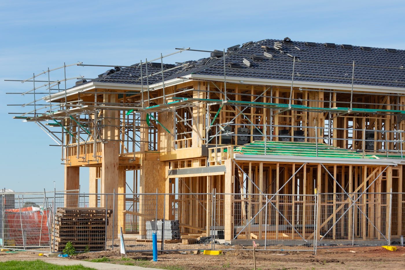 New home construction in South Florida, featuring a partially built house with scaffolding, wooden framing, and construction materials, emphasizing the complexities of custom home building.