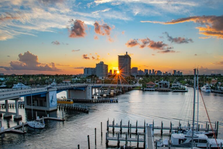 Sunset over West Palm Beach waterfront, featuring a bridge, luxury homes, and boats, highlighting the area's vibrant luxury home construction market.