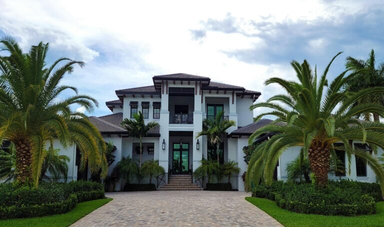 Luxury home exterior in Parkland, FL, featuring modern architecture, palm trees, and landscaped entrance.